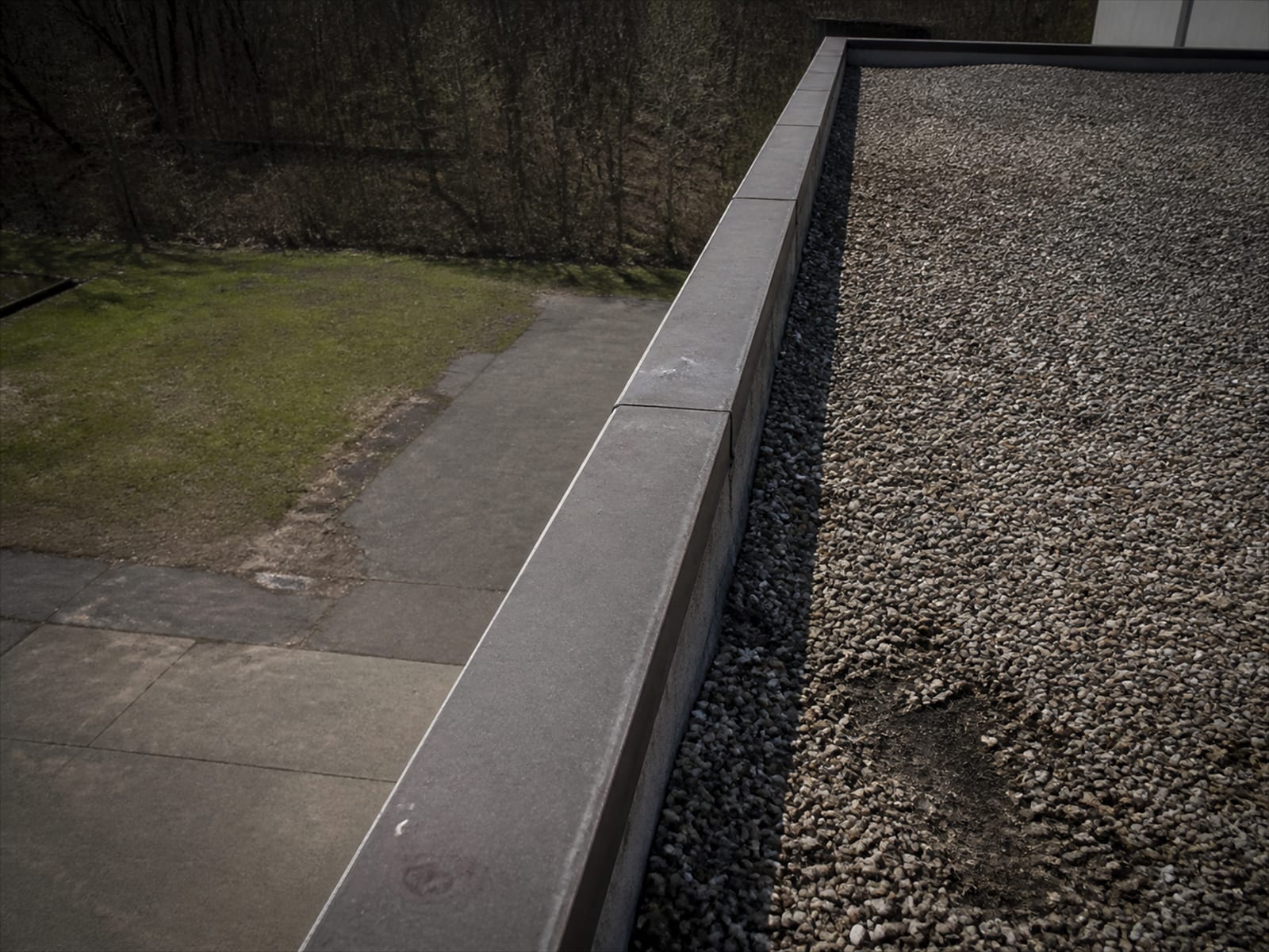 The edge of a flat commercial roof and the drop to the ground below